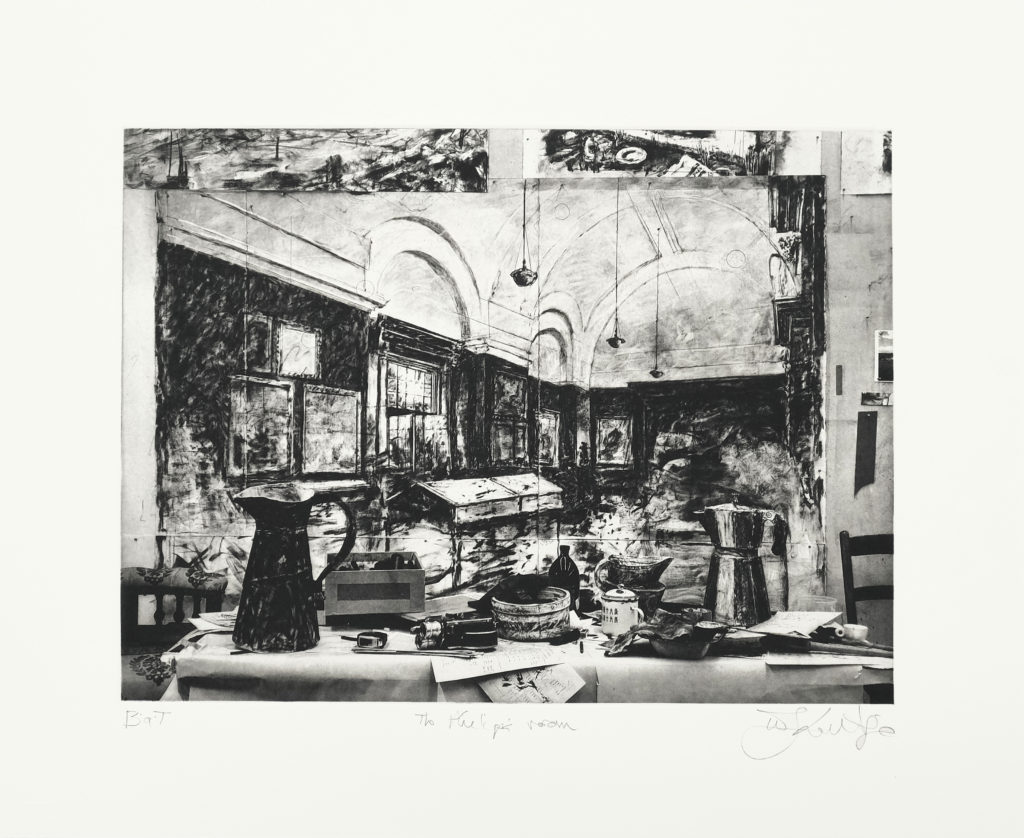 Black and white William Kentridge photogravure print titled The Philips Room with an off-white border. The image is a still life. In the foreground, paper sculptures including an espresso pot, water jug and milk jug sit on a table with other objects. A large charcoal drawing picturing the Philips Room of the Johannesburg Art Gallery hangs on the wall behind the table.